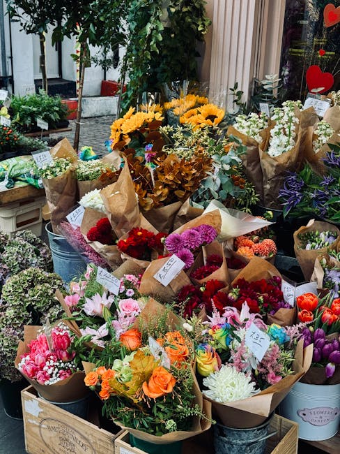 A vibrant display of freshly arranged flower bouquets at Holloway Florist, featuring a variety of flowers including bright sunflowers, pink lilies, orange roses, red carnations, purple irises, and whi
